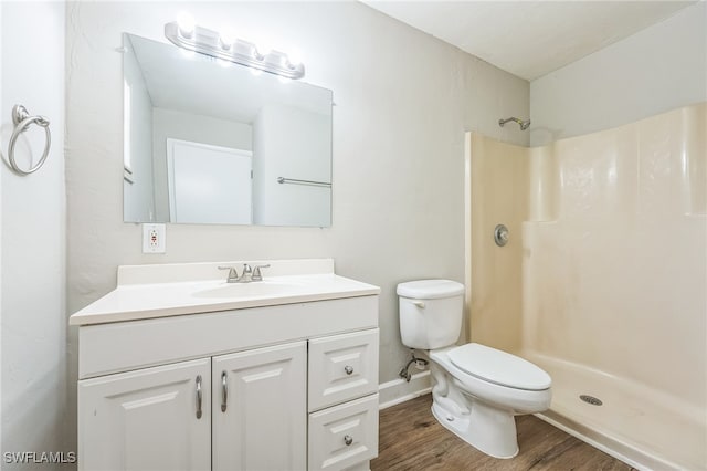 bathroom with a shower, toilet, vanity, and hardwood / wood-style flooring