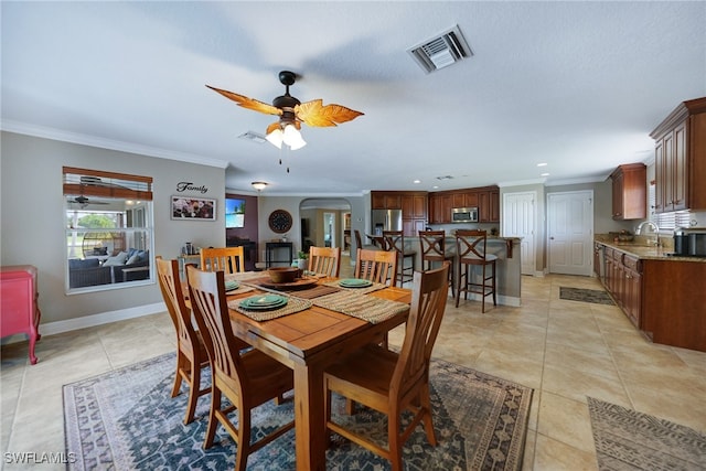 tiled dining area featuring ceiling fan, ornamental molding, and sink