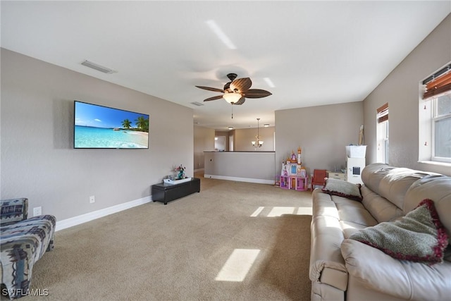 carpeted living room with ceiling fan with notable chandelier