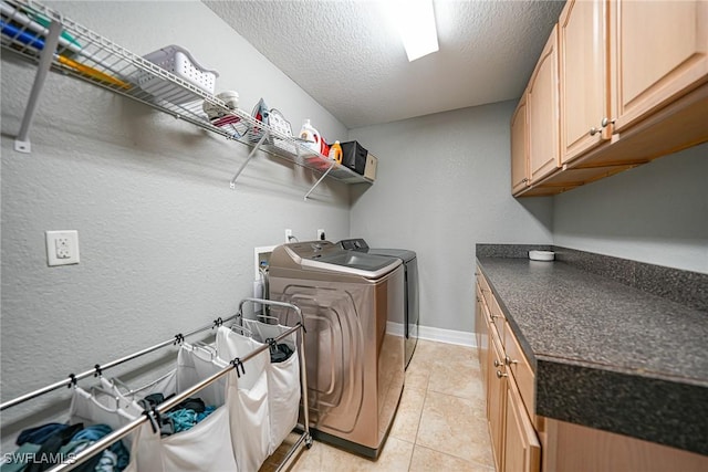 laundry room with cabinets, independent washer and dryer, a textured ceiling, and light tile patterned floors