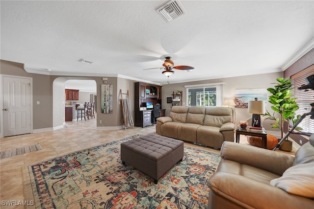 living room with light tile patterned floors, a textured ceiling, ceiling fan, and ornamental molding