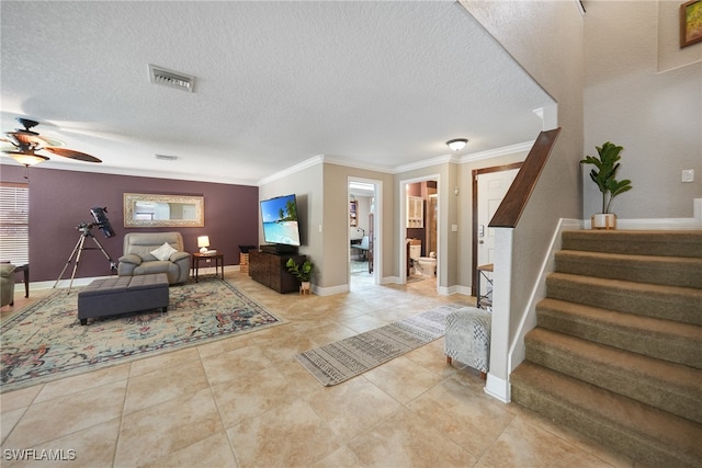 tiled living room featuring ceiling fan, ornamental molding, and a textured ceiling