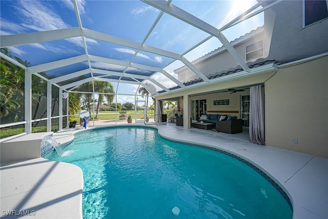 view of pool with outdoor lounge area, pool water feature, ceiling fan, glass enclosure, and a patio area