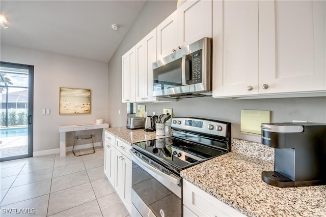 kitchen featuring appliances with stainless steel finishes, light tile patterned flooring, white cabinetry, light stone countertops, and baseboards