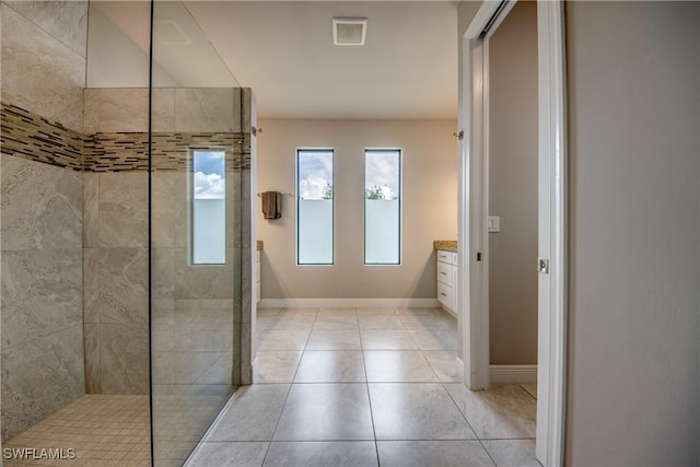 full bathroom featuring tile patterned floors, vanity, baseboards, and walk in shower