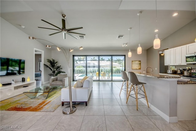 living area with vaulted ceiling, light tile patterned floors, visible vents, and a ceiling fan