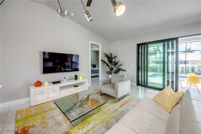 tiled living area featuring vaulted ceiling and baseboards