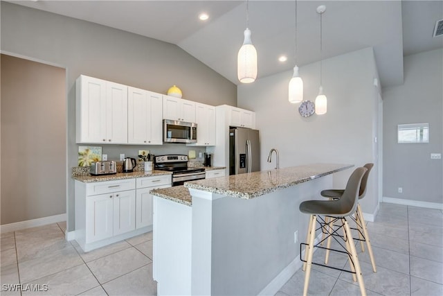 kitchen featuring stainless steel appliances, a breakfast bar, light stone counters, and white cabinets