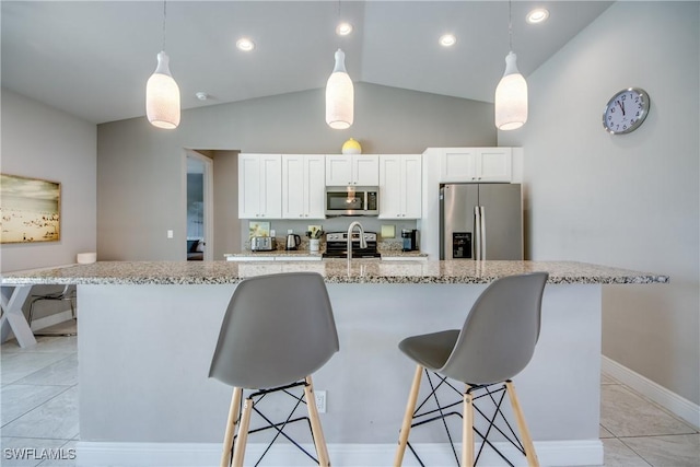 kitchen featuring a kitchen bar, appliances with stainless steel finishes, white cabinets, and a center island with sink