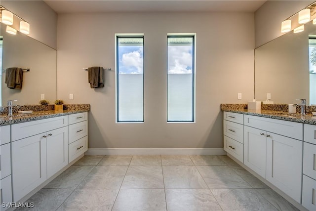 bathroom featuring two vanities, a sink, and baseboards