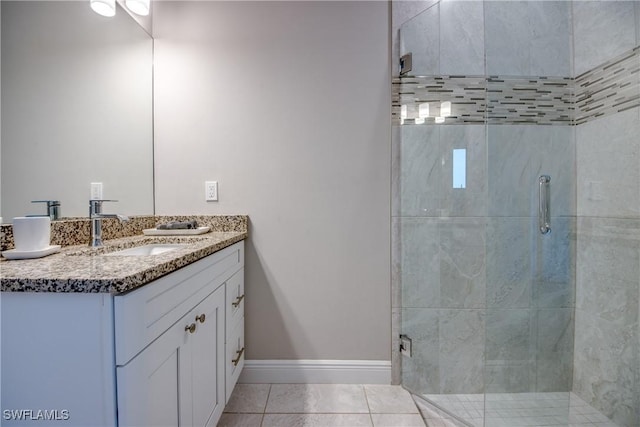 bathroom with double vanity, baseboards, tile patterned flooring, a shower stall, and a sink