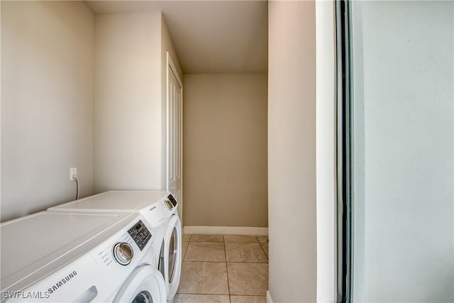 laundry room with baseboards, light tile patterned flooring, and washing machine and clothes dryer