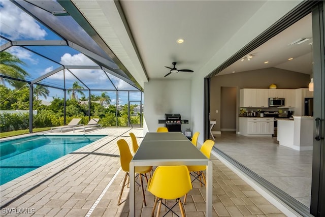 outdoor pool featuring glass enclosure, a patio area, ceiling fan, and an outdoor kitchen