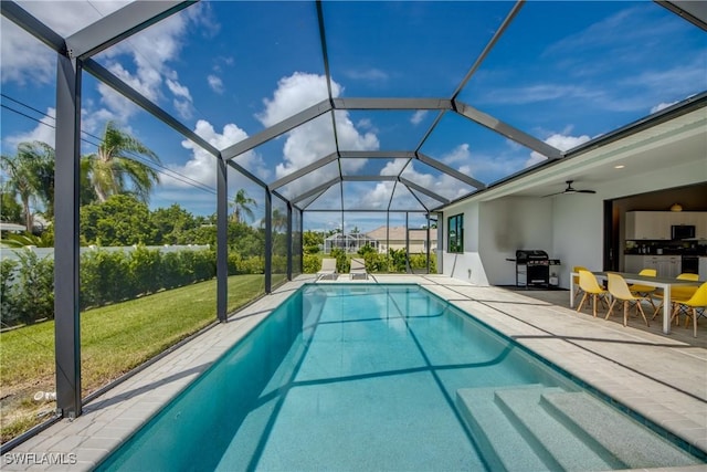 pool featuring a yard, a patio, area for grilling, glass enclosure, and ceiling fan