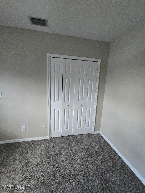 unfurnished bedroom with a closet, a textured ceiling, and carpet floors