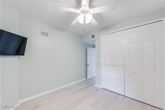 unfurnished bedroom with ceiling fan, a closet, and light wood-type flooring