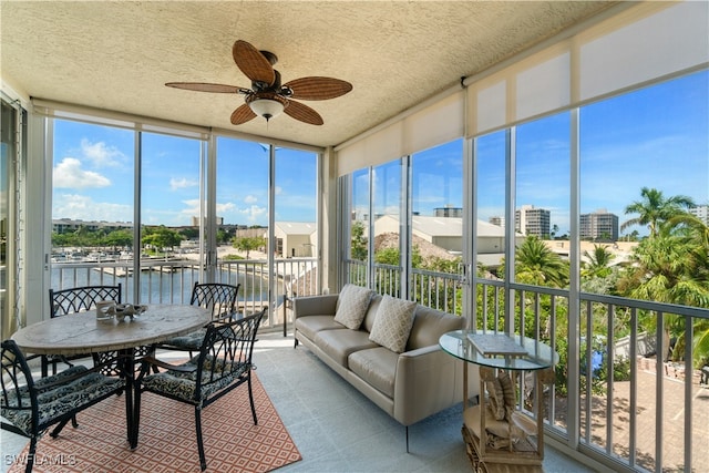 sunroom / solarium featuring a water view and ceiling fan