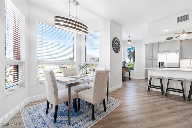 dining area with ceiling fan with notable chandelier and hardwood / wood-style floors