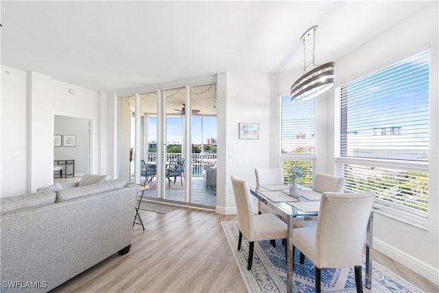 dining space with a healthy amount of sunlight, wood-type flooring, and a notable chandelier