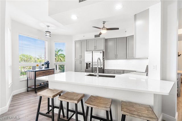 kitchen featuring light hardwood / wood-style flooring, sink, stainless steel fridge, ceiling fan, and tasteful backsplash