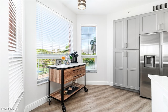 kitchen with a wealth of natural light, light hardwood / wood-style floors, gray cabinetry, and built in refrigerator