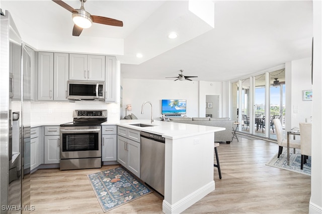 kitchen with ceiling fan, sink, appliances with stainless steel finishes, and kitchen peninsula