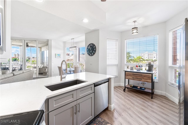 kitchen featuring plenty of natural light, stainless steel dishwasher, sink, and hanging light fixtures