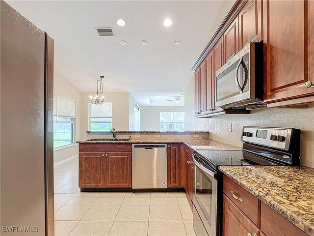 kitchen with ceiling fan with notable chandelier, light stone countertops, appliances with stainless steel finishes, kitchen peninsula, and sink