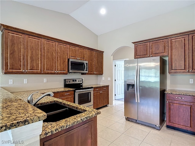 kitchen featuring vaulted ceiling, light stone countertops, stainless steel appliances, sink, and light tile patterned flooring