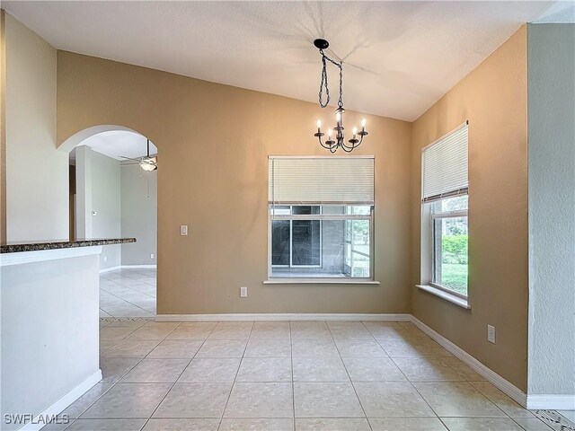 tiled empty room with ceiling fan with notable chandelier and lofted ceiling