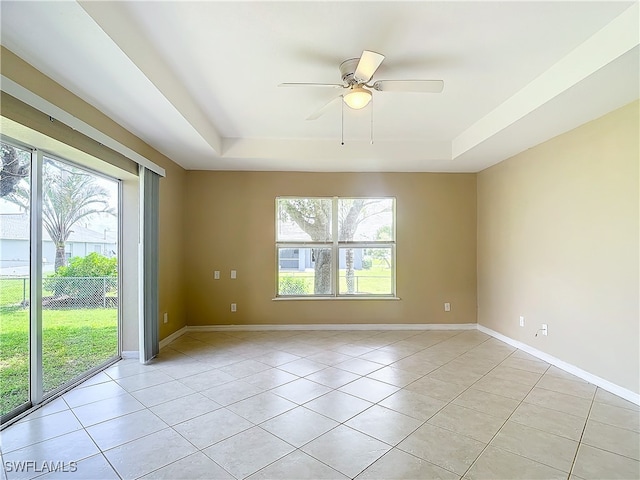 tiled spare room featuring a tray ceiling and ceiling fan