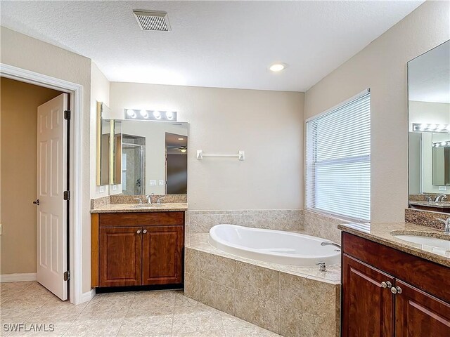 bathroom with a textured ceiling, vanity, tile patterned flooring, and shower with separate bathtub