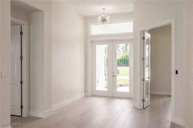 doorway with light wood-style floors, french doors, a chandelier, and baseboards