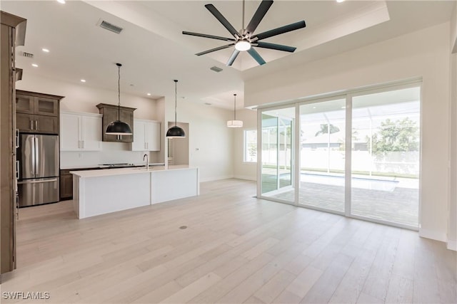 kitchen with light wood-style floors, freestanding refrigerator, light countertops, and visible vents