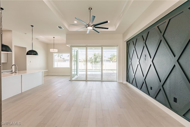 spare room with a raised ceiling, ceiling fan, sink, and light hardwood / wood-style floors