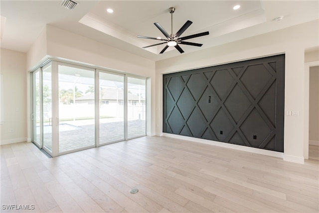 spare room featuring plenty of natural light, ceiling fan, a raised ceiling, and light wood-type flooring