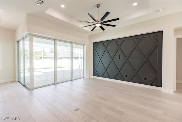 unfurnished room with recessed lighting, visible vents, baseboards, a tray ceiling, and light wood finished floors