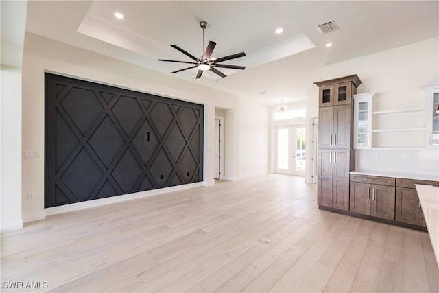 unfurnished living room featuring visible vents, a tray ceiling, light wood-style flooring, and recessed lighting