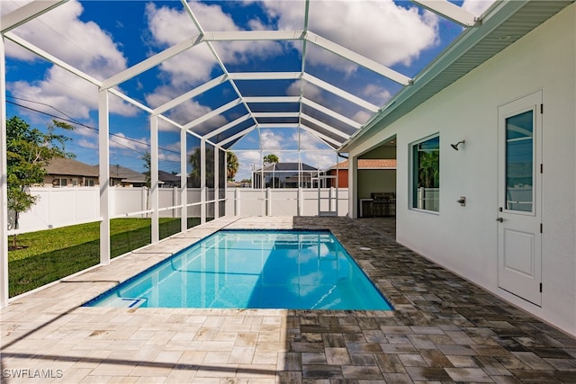 view of pool featuring a yard, a patio area, and glass enclosure