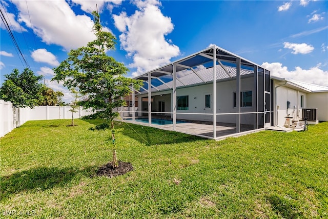 rear view of property featuring a patio, a lanai, a fenced in pool, a yard, and central AC unit