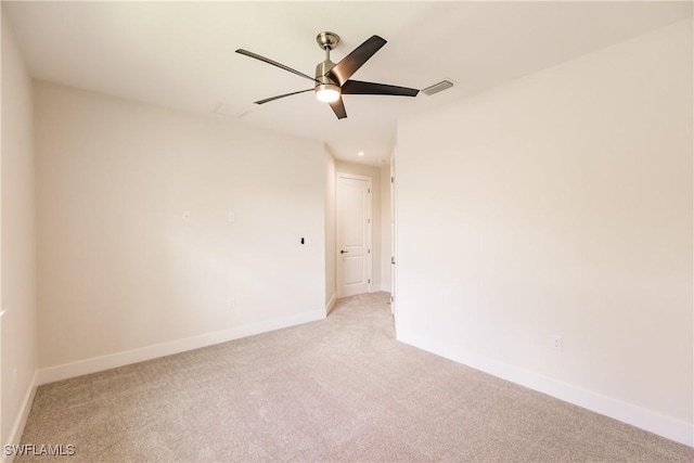 spare room featuring light carpet, ceiling fan, visible vents, and baseboards