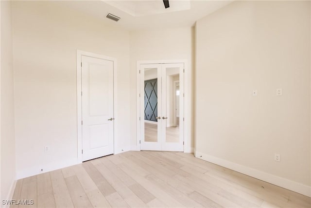 unfurnished room with french doors, light wood-style flooring, visible vents, and baseboards