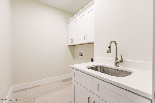 washroom featuring light wood-type flooring, hookup for an electric dryer, sink, washer hookup, and cabinets