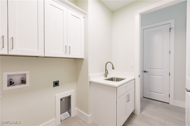 washroom featuring light wood-type flooring, electric dryer hookup, sink, washer hookup, and cabinets