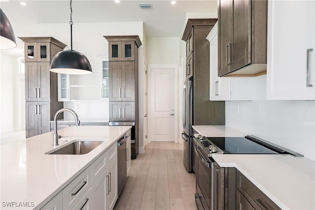 kitchen featuring a sink, visible vents, light countertops, appliances with stainless steel finishes, and hanging light fixtures