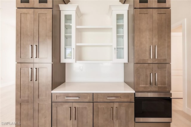 kitchen with open shelves, glass insert cabinets, light countertops, and oven