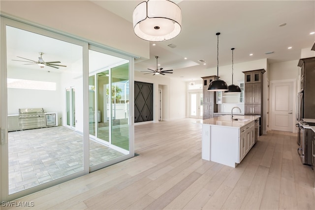 kitchen with a wealth of natural light, pendant lighting, ceiling fan, and a kitchen island with sink