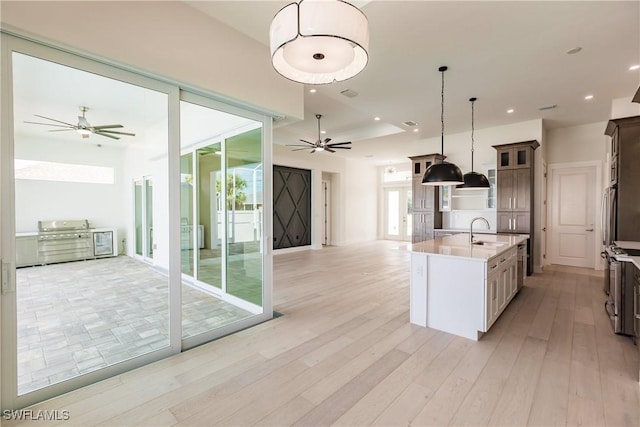 kitchen featuring a sink, light wood-style floors, open floor plan, light countertops, and decorative light fixtures