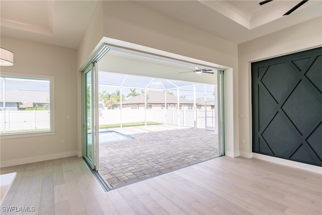 doorway featuring a tray ceiling, light hardwood / wood-style flooring, and ceiling fan