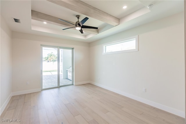 spare room with light wood-type flooring, a raised ceiling, and ceiling fan